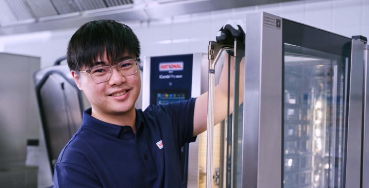 工作人员操作RATIONAL iCombi Pro 混合蒸锅的开门机构，展示设备结构与细节。